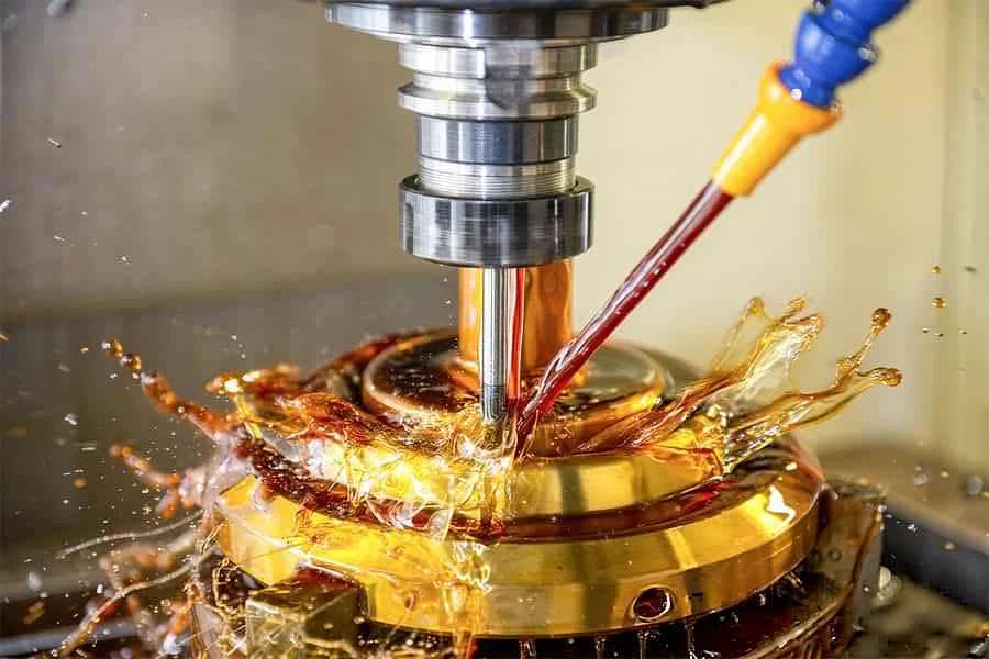 CNC turning with coolant flushing the cut on a brass component