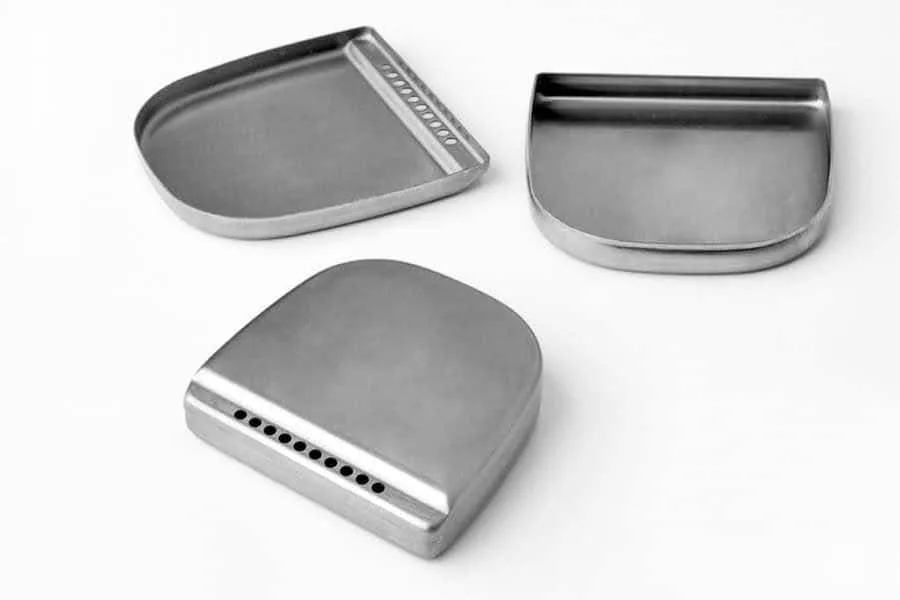 Three formed titanium shells with drawn walls and radii on a white background